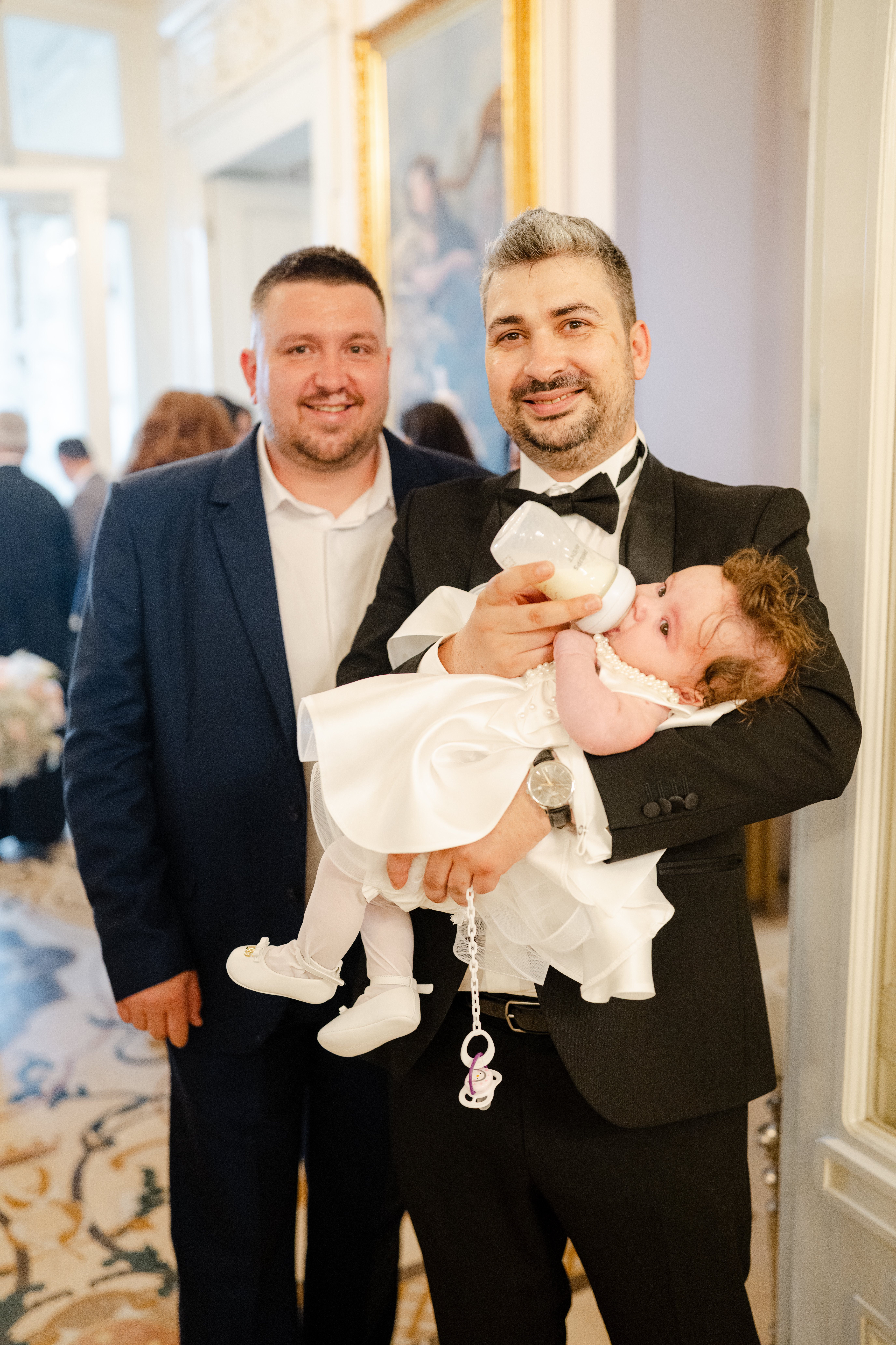Nași cu bebeluș în rochița albă de botez — holul Palatului Noblesse