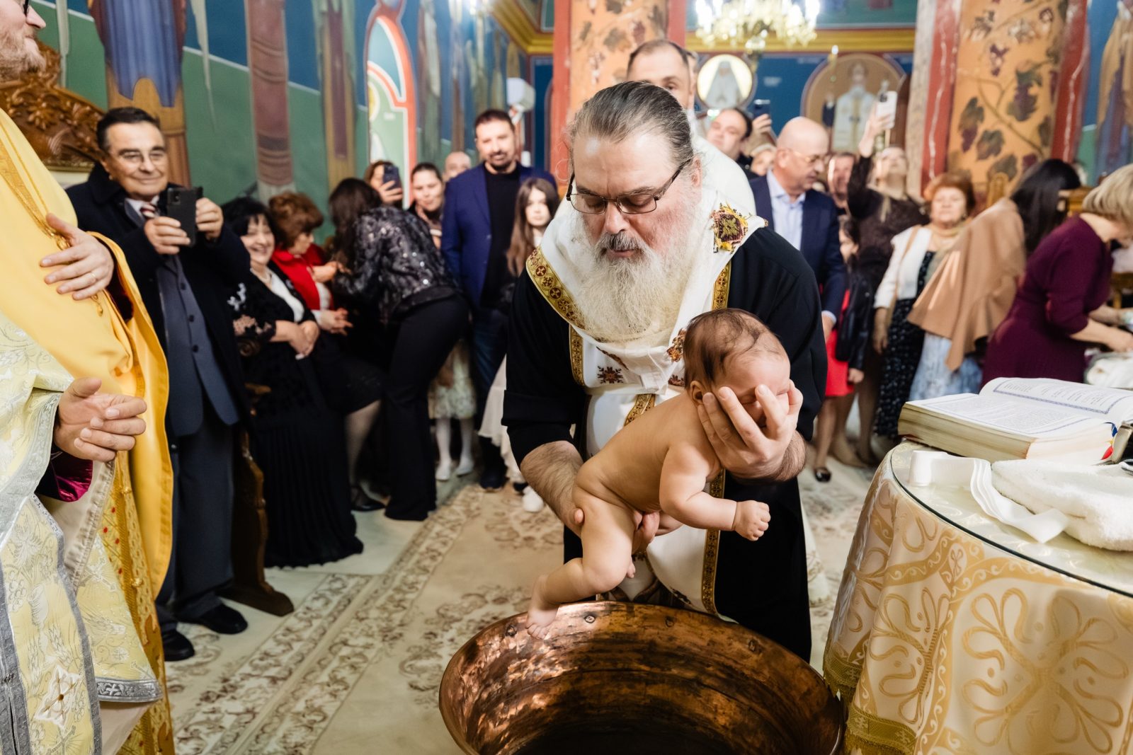 Cufundarea copilului în apa botezului de către preot