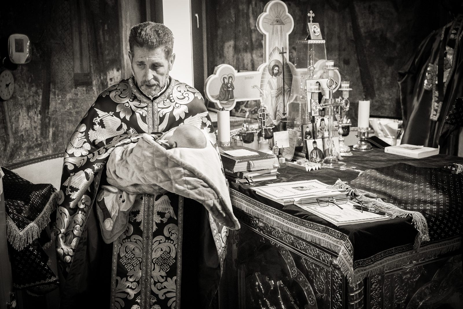 Preotul cu bebelușul la altar în timpul botezului ortodox, tradiții românești