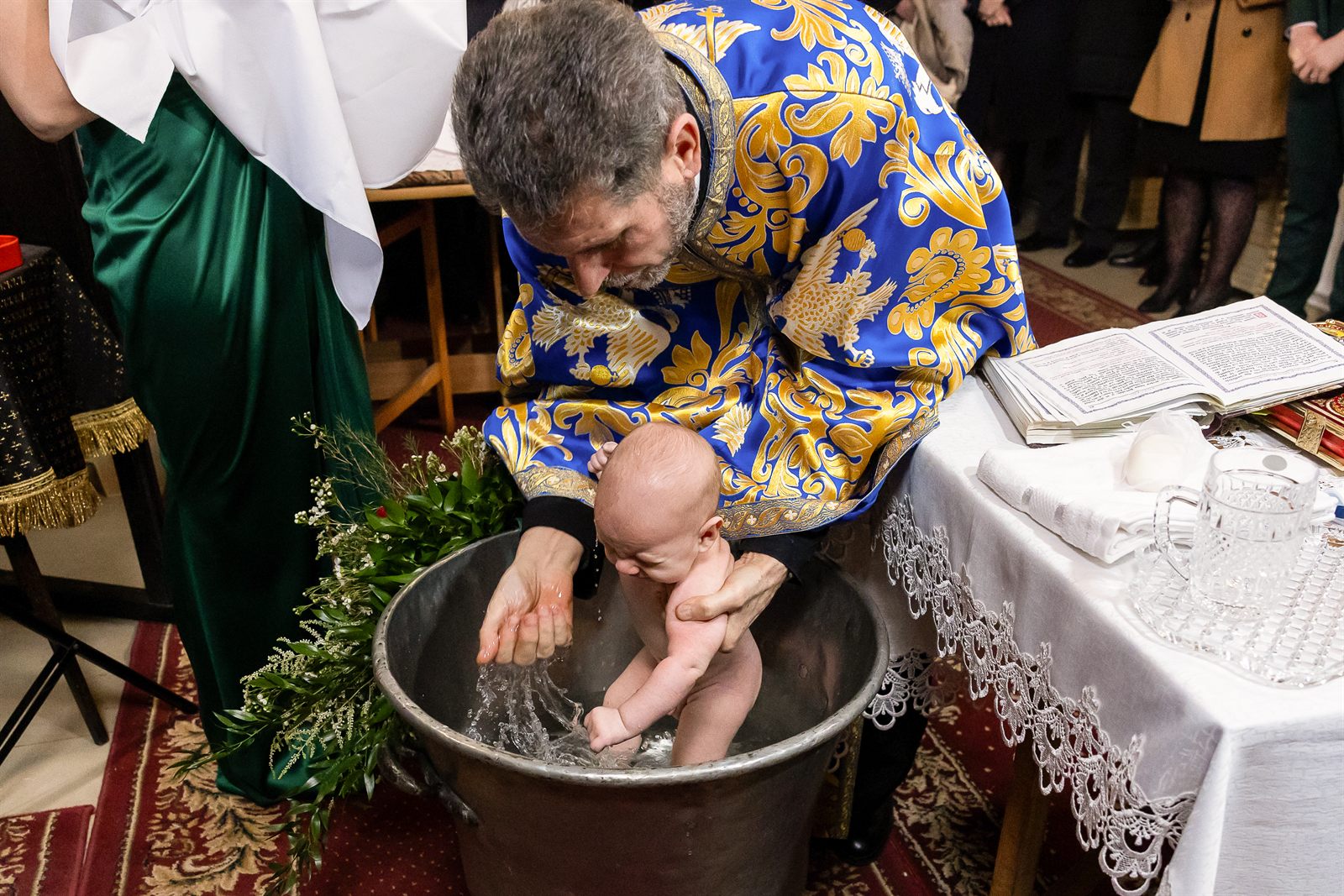 Scalda — preotul cufundând bebelușul în cristelniță la botezul ortodox, tradiții românești