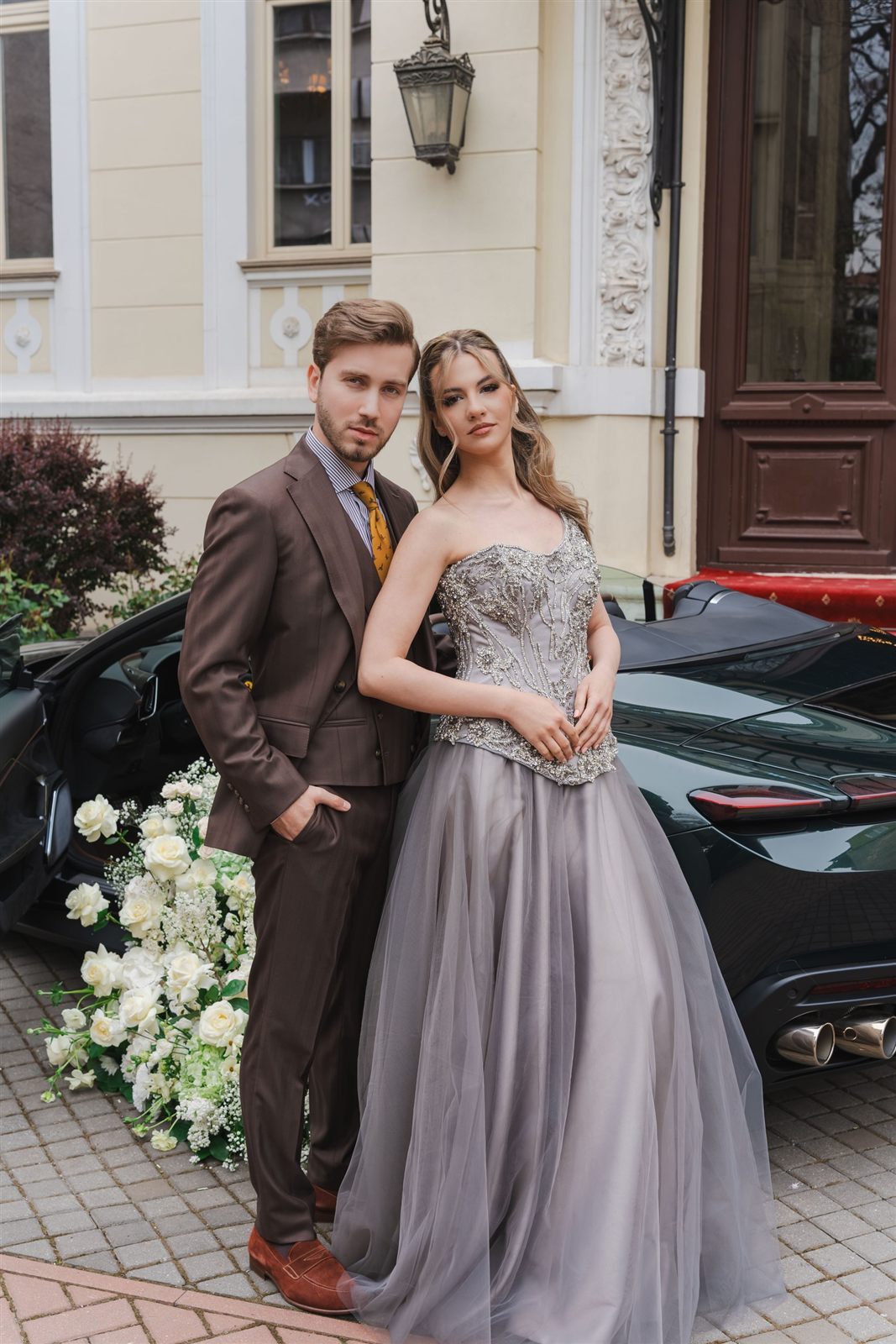 Cuplu elegant — bărbat în costum cu cravată și doamnă în rochie lungă de seară, la Palatul Noblesse