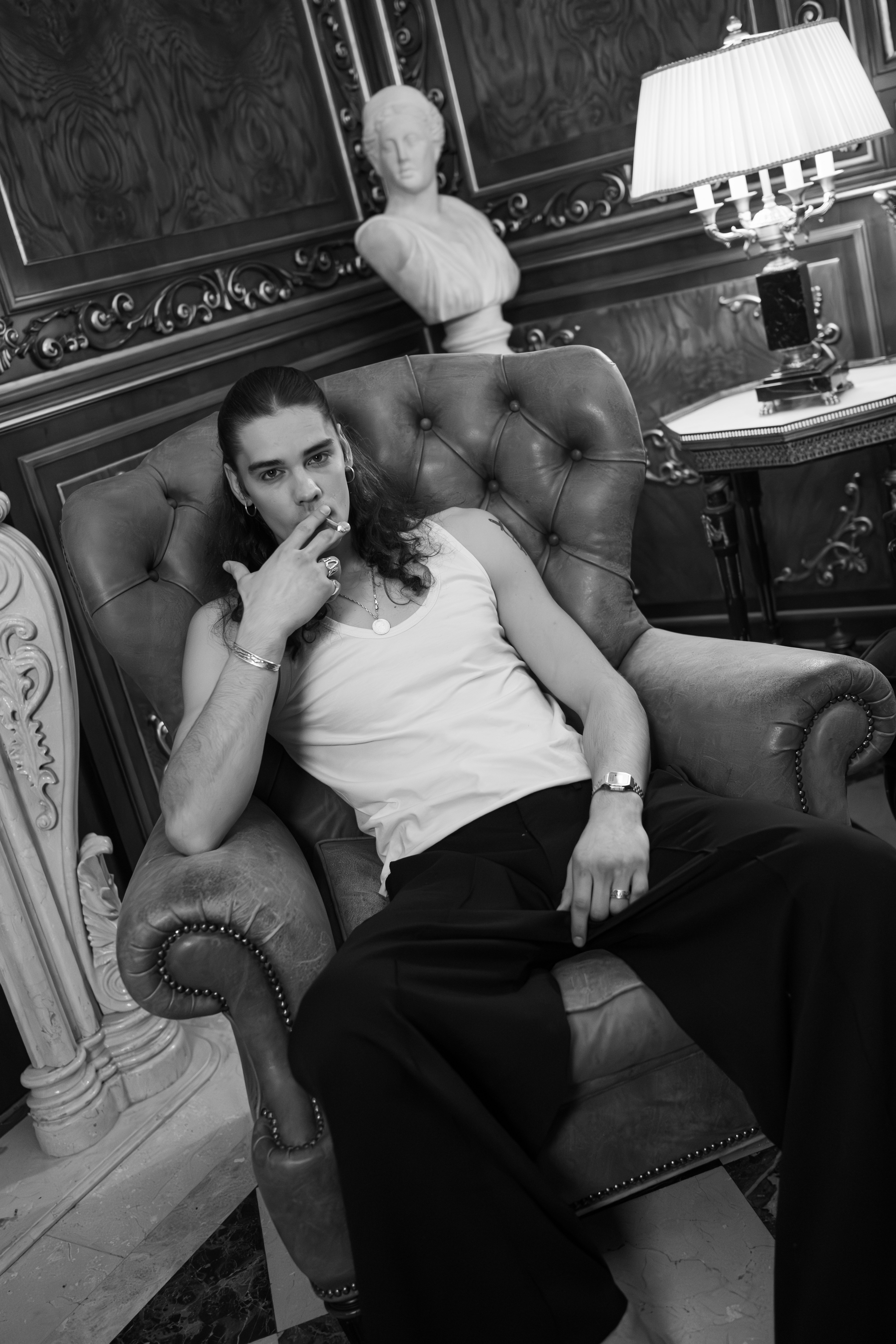 Model masculin în fotoliu Chesterfield salonul întunecat — editorial noir Palatul Noblesse