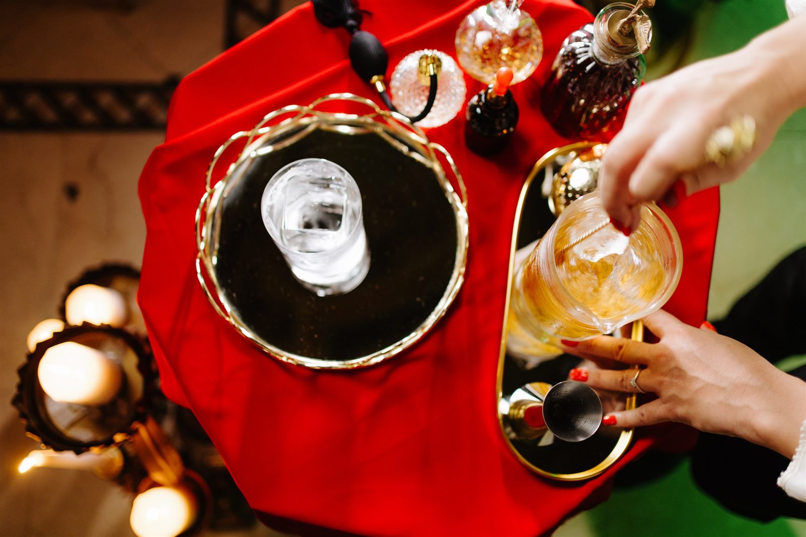 Mixolog pregătind un cocktail signature în pahar de cristal, pe o stație de bar cu catifea roșie