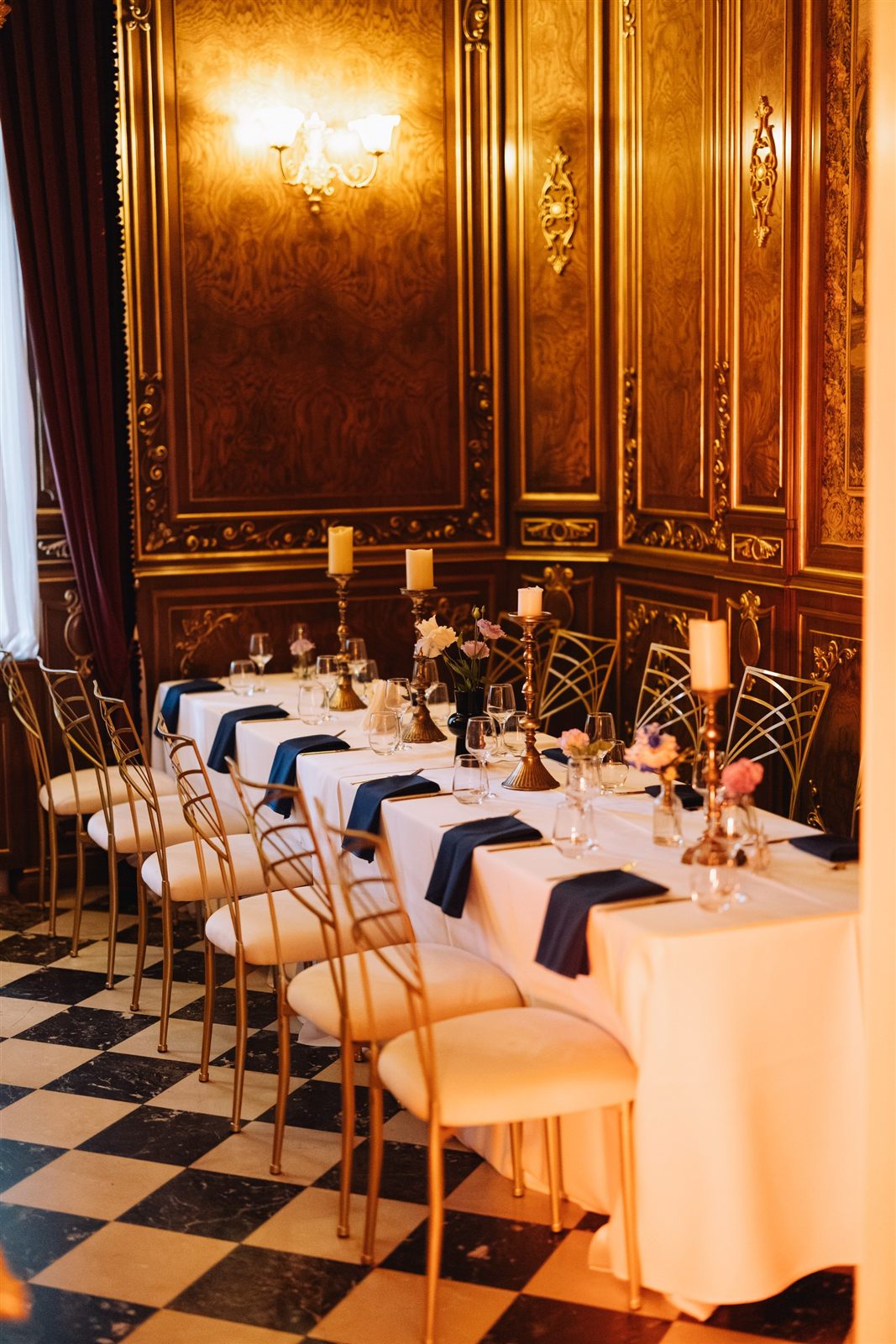 Decor de masă cu tacâmuri aurii și șervete bleumarin într-un salon cu pardoseală în damier, Palatul Noblesse