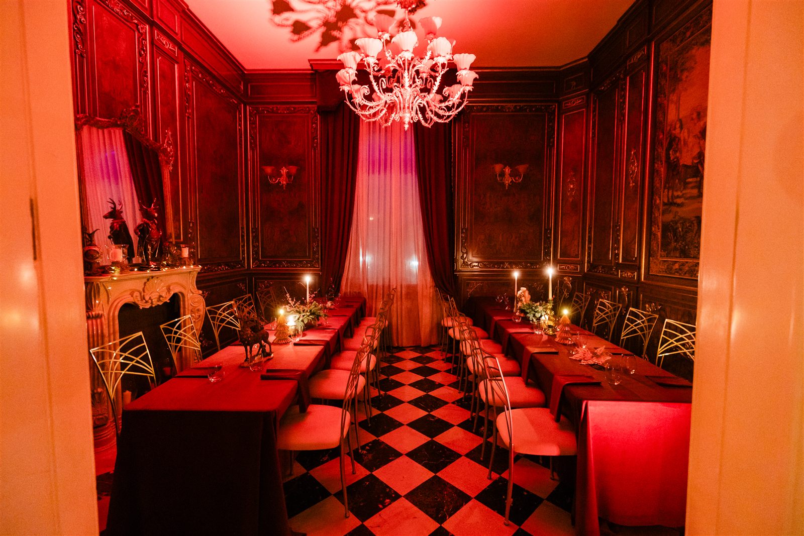 Salonul Regent cu mese roșii și lumânări, decor de bal mascat