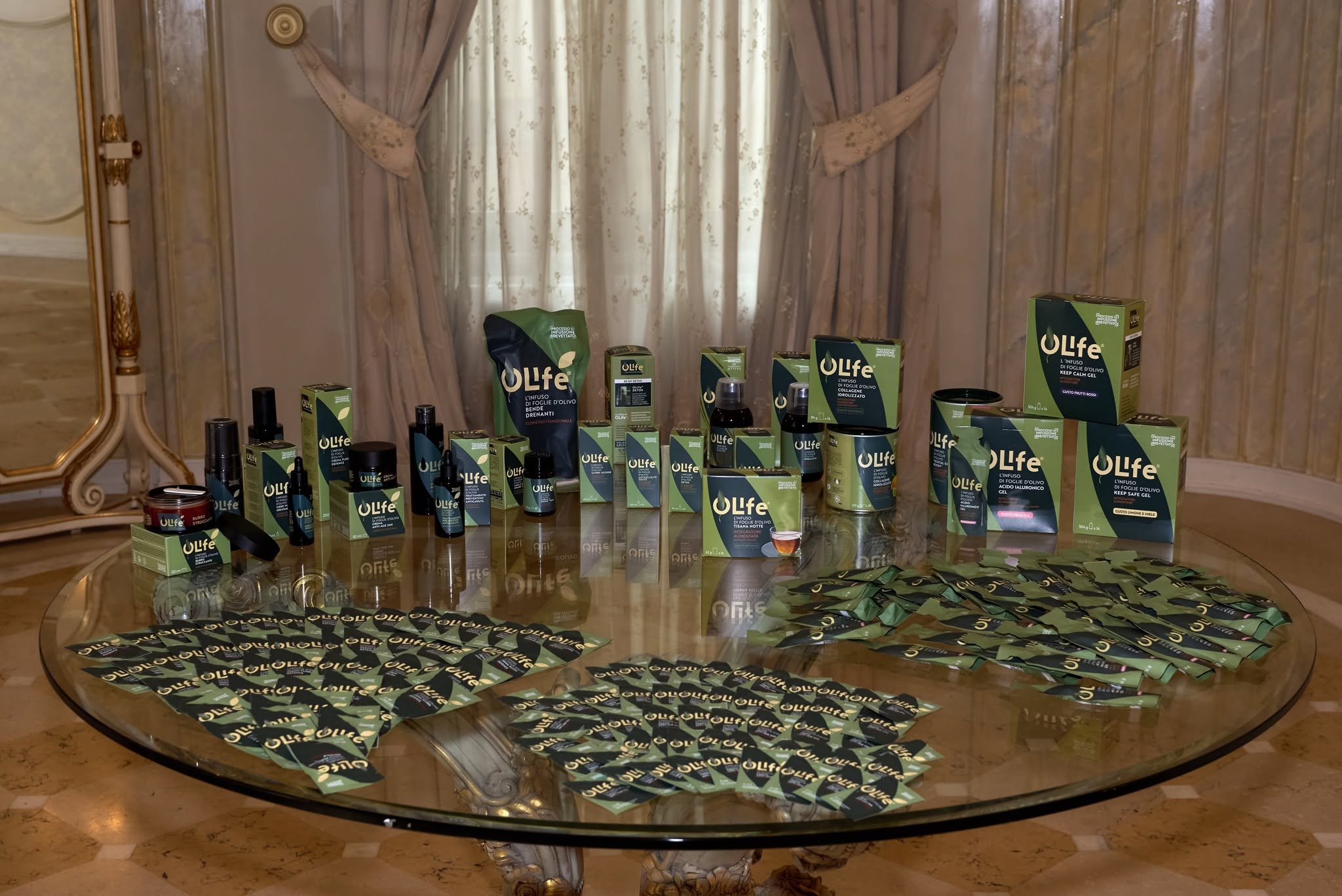 Gama completă produse OLife Evergreen Life expusă pe masă rotundă din sticlă — salon Palatul Noblesse, EVERDREAM 2026