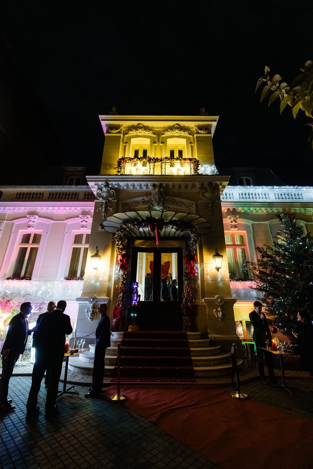 Fatada Palatului Noblesse iluminata si decorata de Craciun seara, cu invitati la intrare