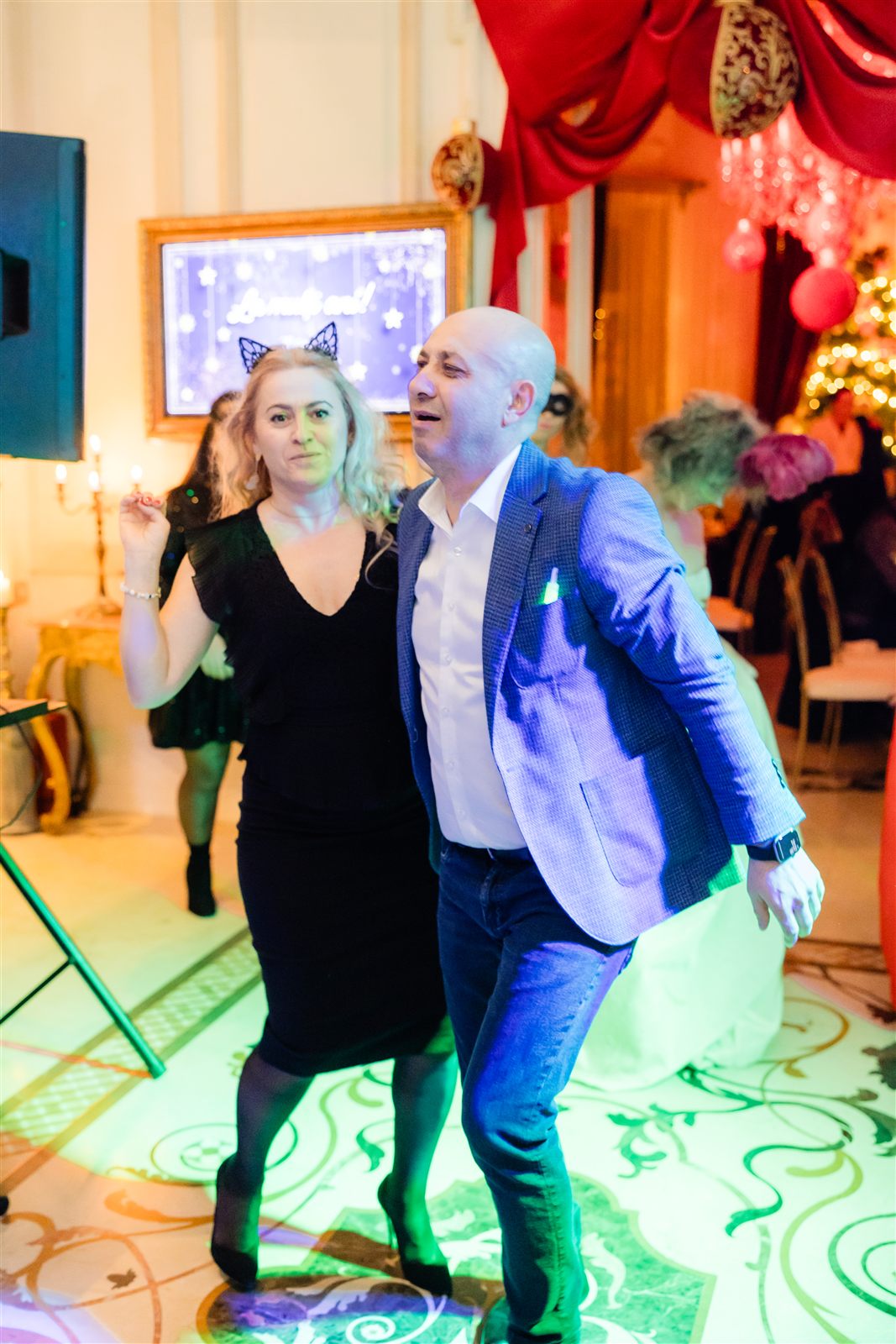 Pereche dansând în lumini colorate la balul mascat