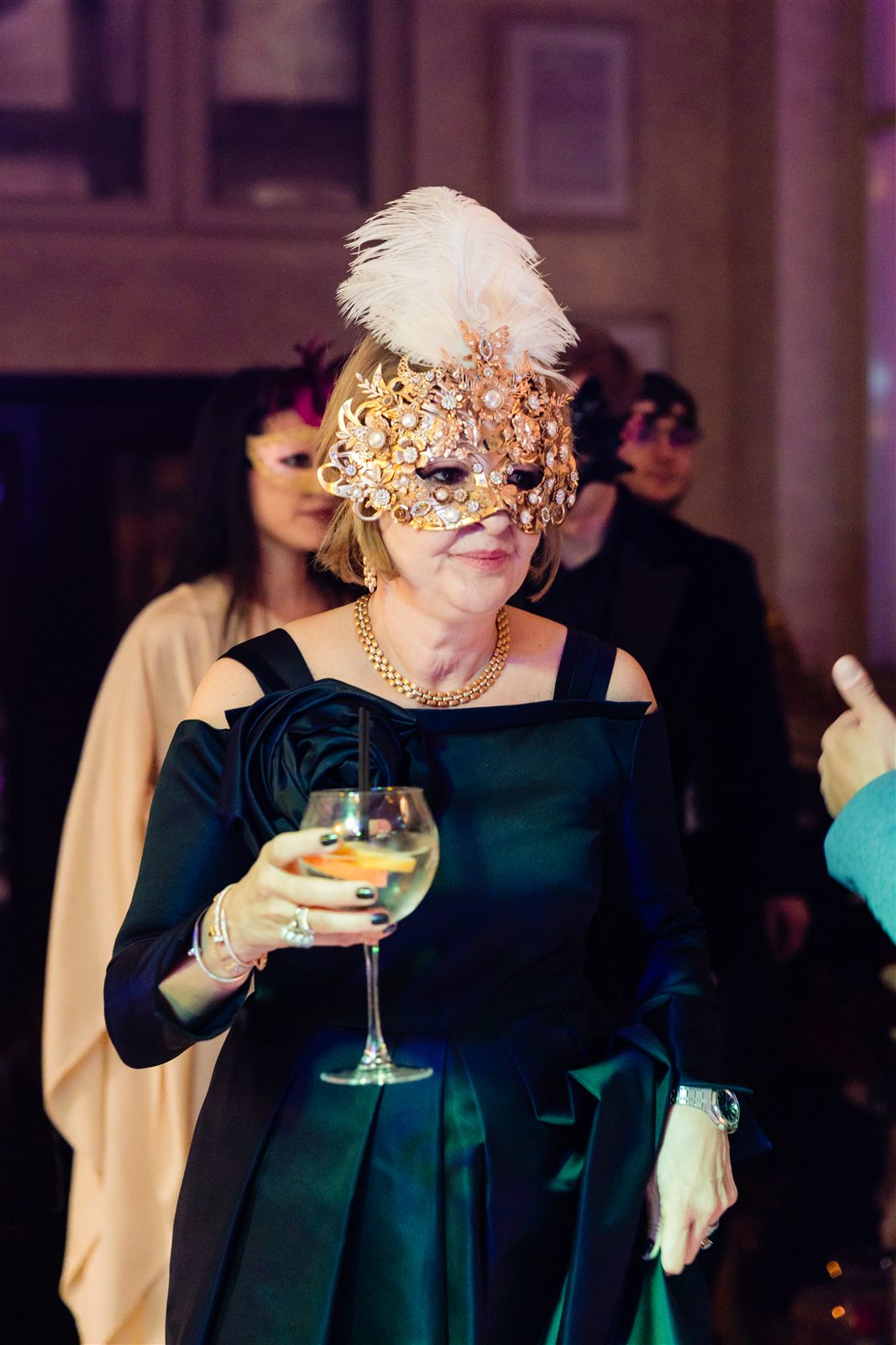 Invitată cu mască aurie și pahar de spumant