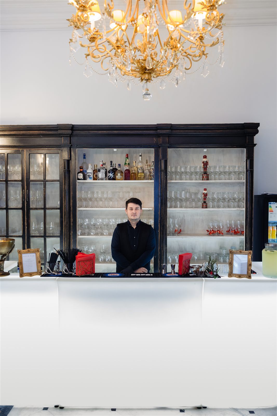 Barul Palatului Noblesse sub candelabrul aurit, cu bartender și meniu open bar