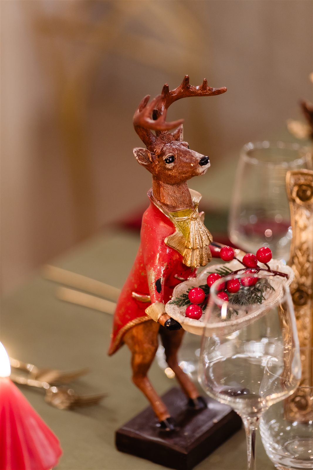Figurină de cerb roșu cu pahar de cristal pe masa festivă, decor de Crăciun