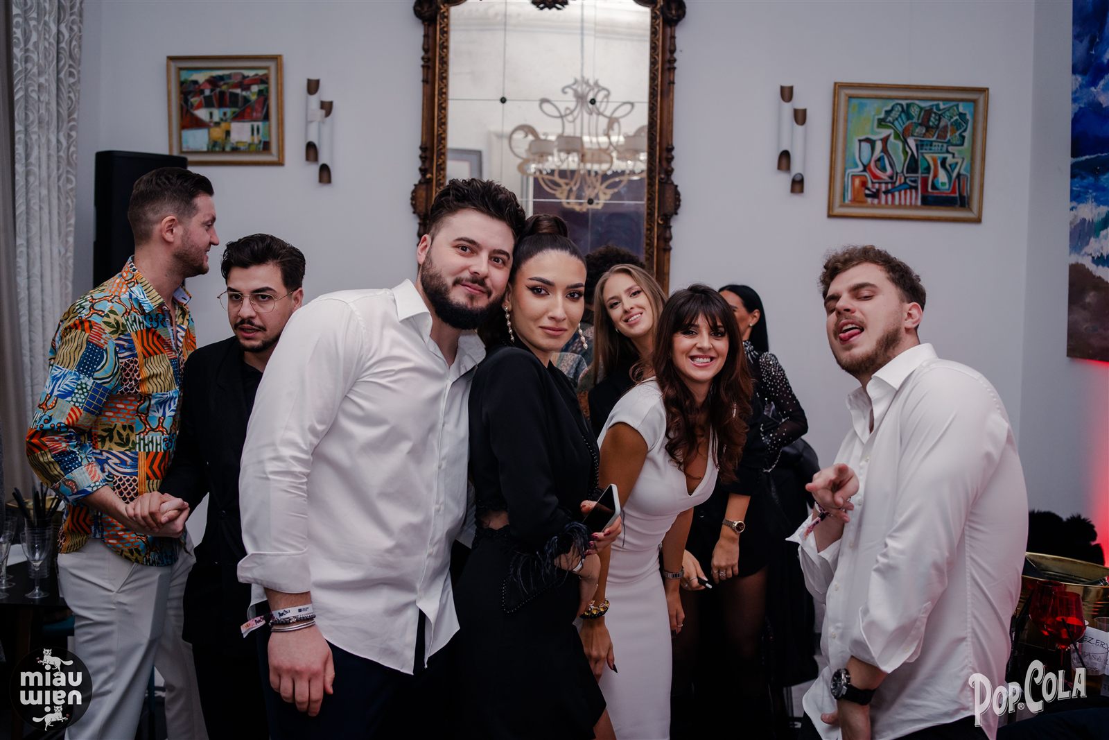 Grup de invitați într-un salon alb cu tablouri, petrecere de Revelion
