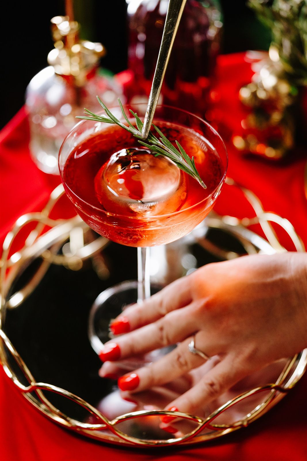 Cocktail roșu cu rozmarin pe tavă aurie