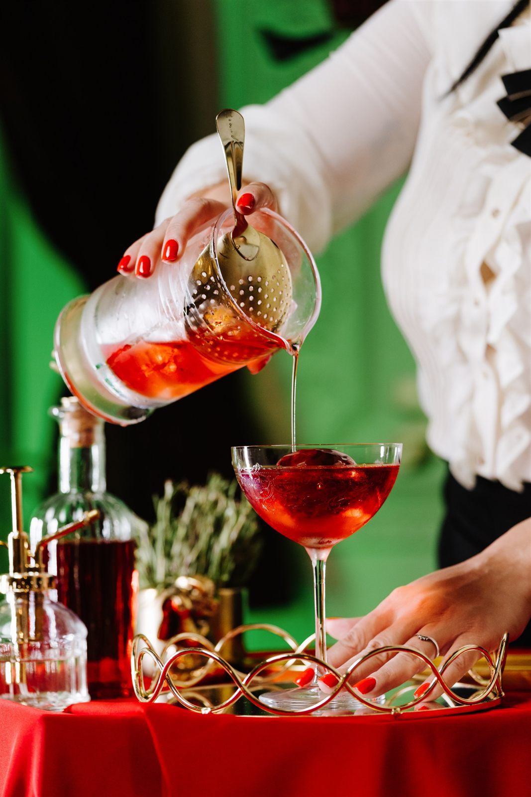 Cocktail roșu turnat în pahar de cristal, cocktail signature de Crăciun