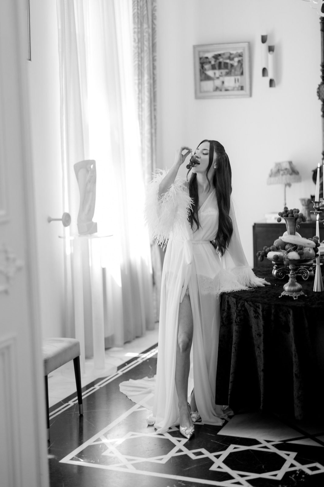 Mireasă lângă fereastră cu lumina naturală — Palatul Noblesse, efect editorial alb-negru