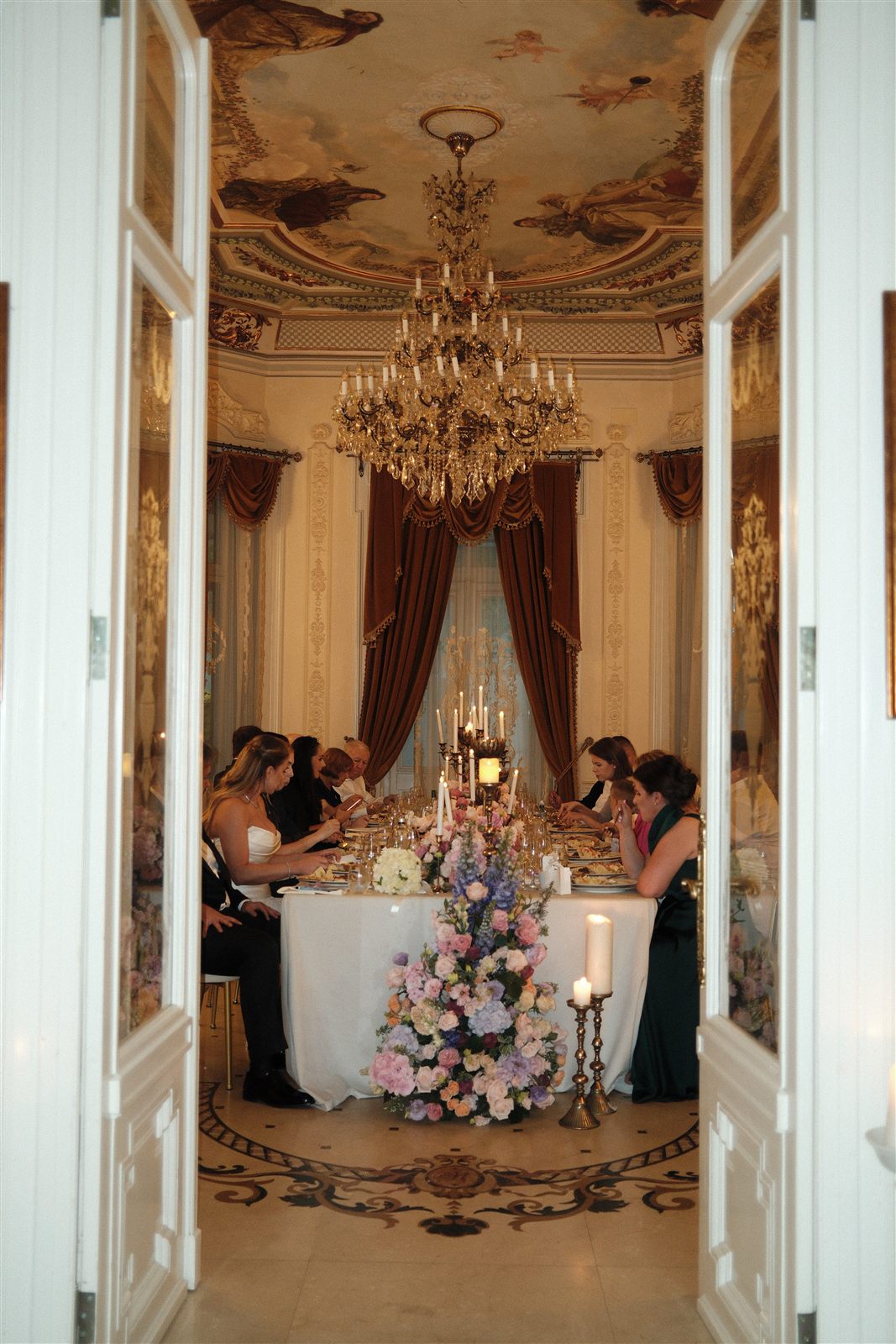 Masa decorata din Salonul Baroque cu invitati, vazuta prin usi, la cununia de la Palatul Noblesse
