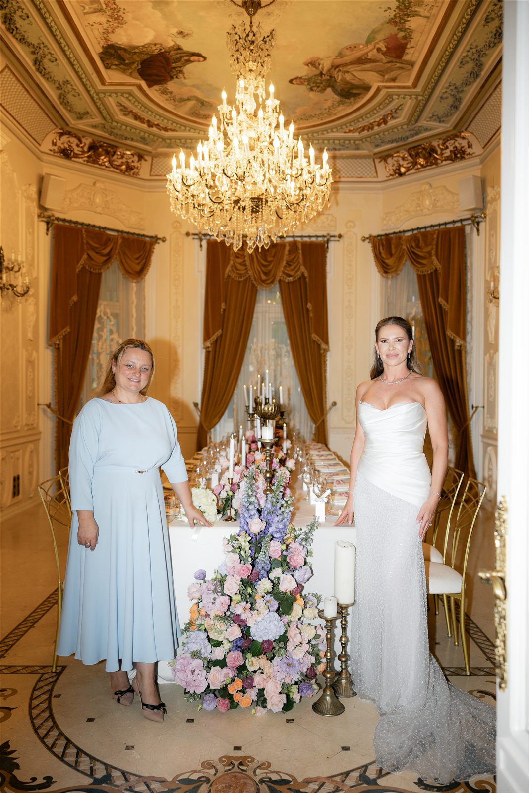 Mireasa alaturi de o persoana draga langa masa decorata la Palatul Noblesse