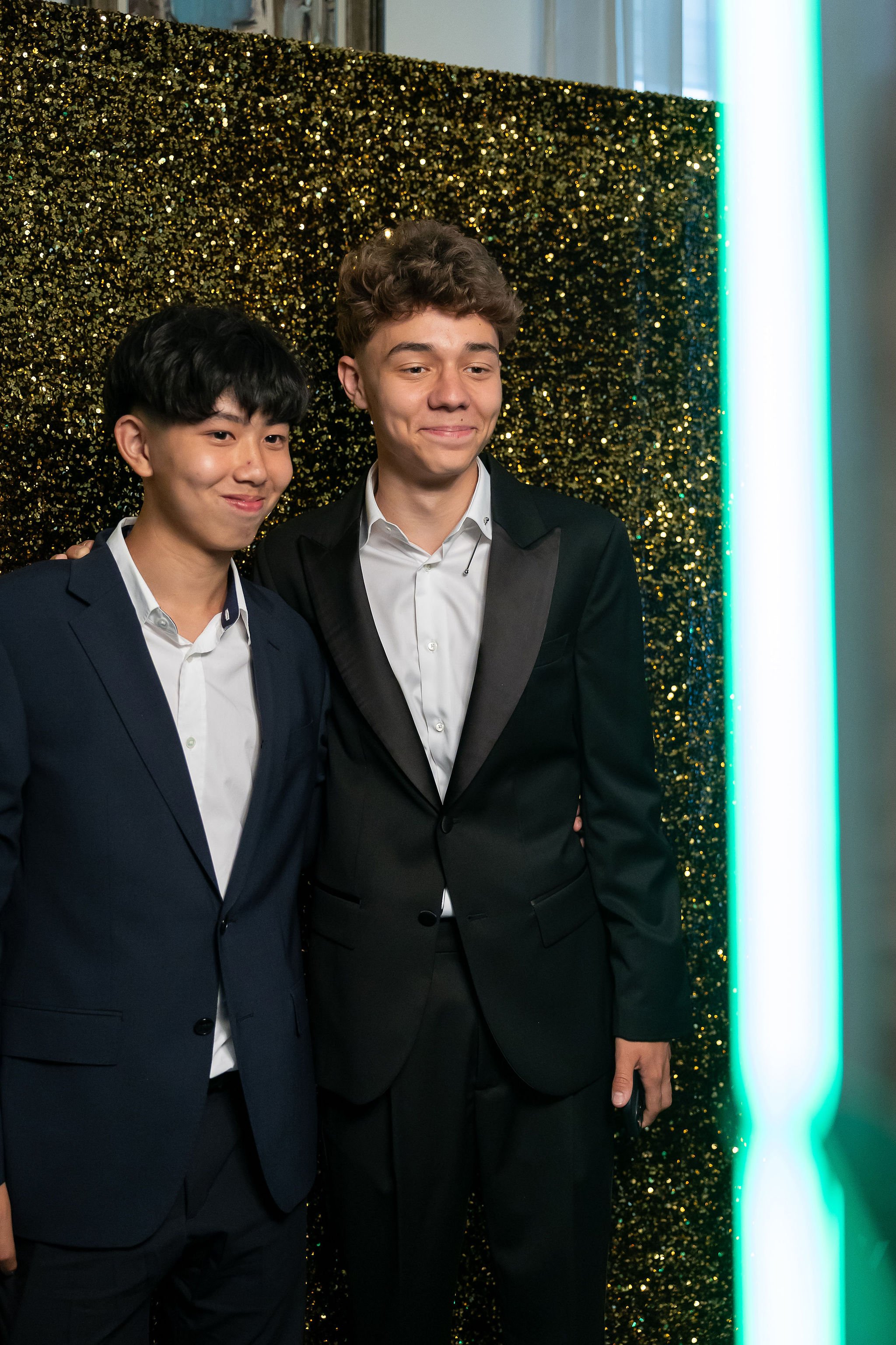 Doi elevi la photo booth cu fundal sclipici auriu — banchet Cambridge School Palatul Noblesse