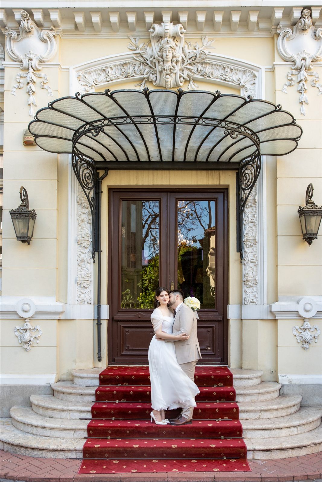 Portret de cuplu la intrarea cu covor roșu a Palatului Noblesse — ședință foto de cununie