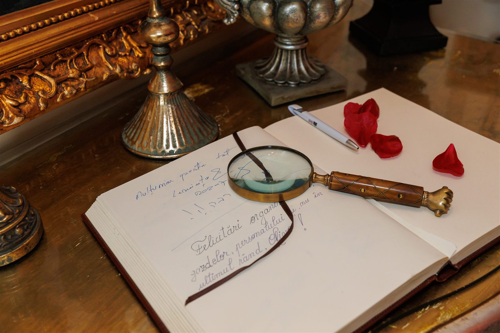 Guest book cu petale de trandafir și lupă vintage — detaliu de eveniment tematic