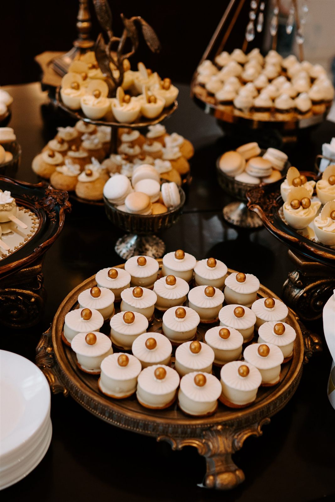 Candy bar de nuntă cu mini-prăjituri pe platouri aurii — tematică alb-auriu