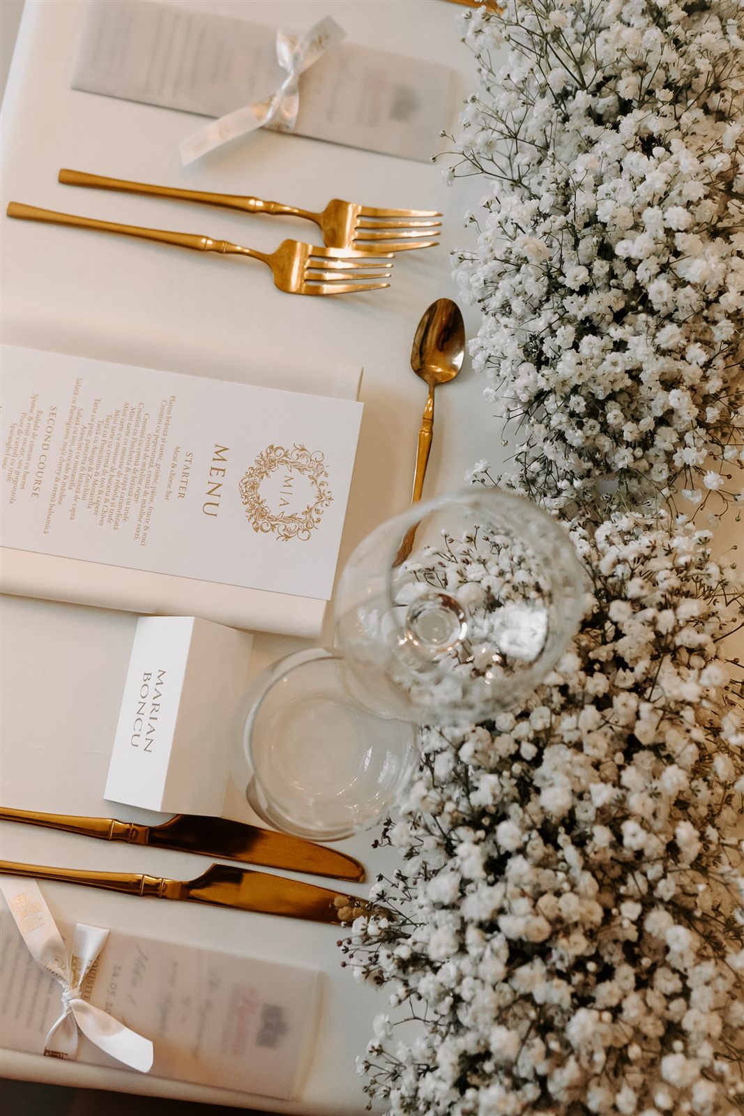 Place setting cu tacâmuri aurii și floarea-miresei — decor de nuntă coordonat