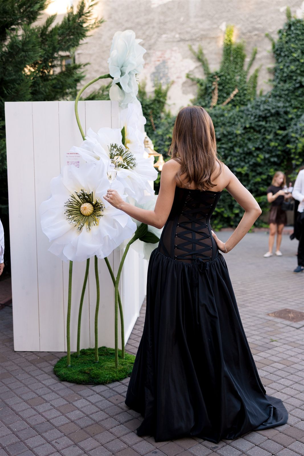 Invitata langa floarea alba supradimensionata a peretelui interactiv Ring for Drinks Wall