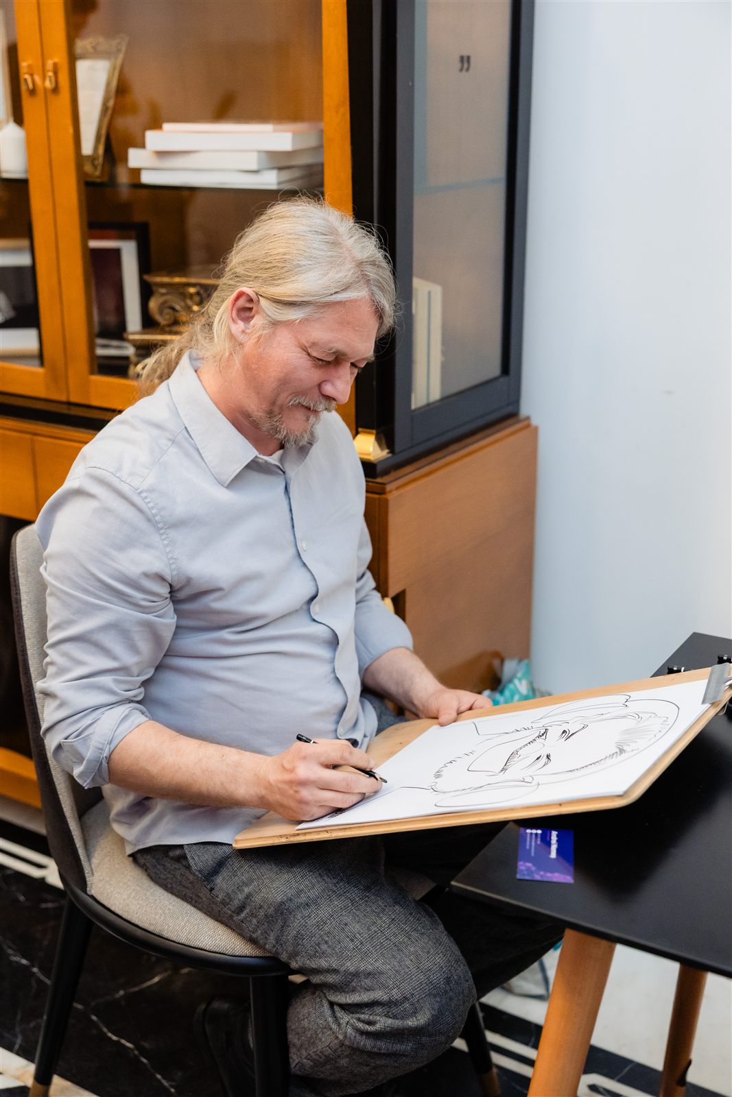 Caricaturistul arată caricatura finalizată unui invitat — Palatul Noblesse